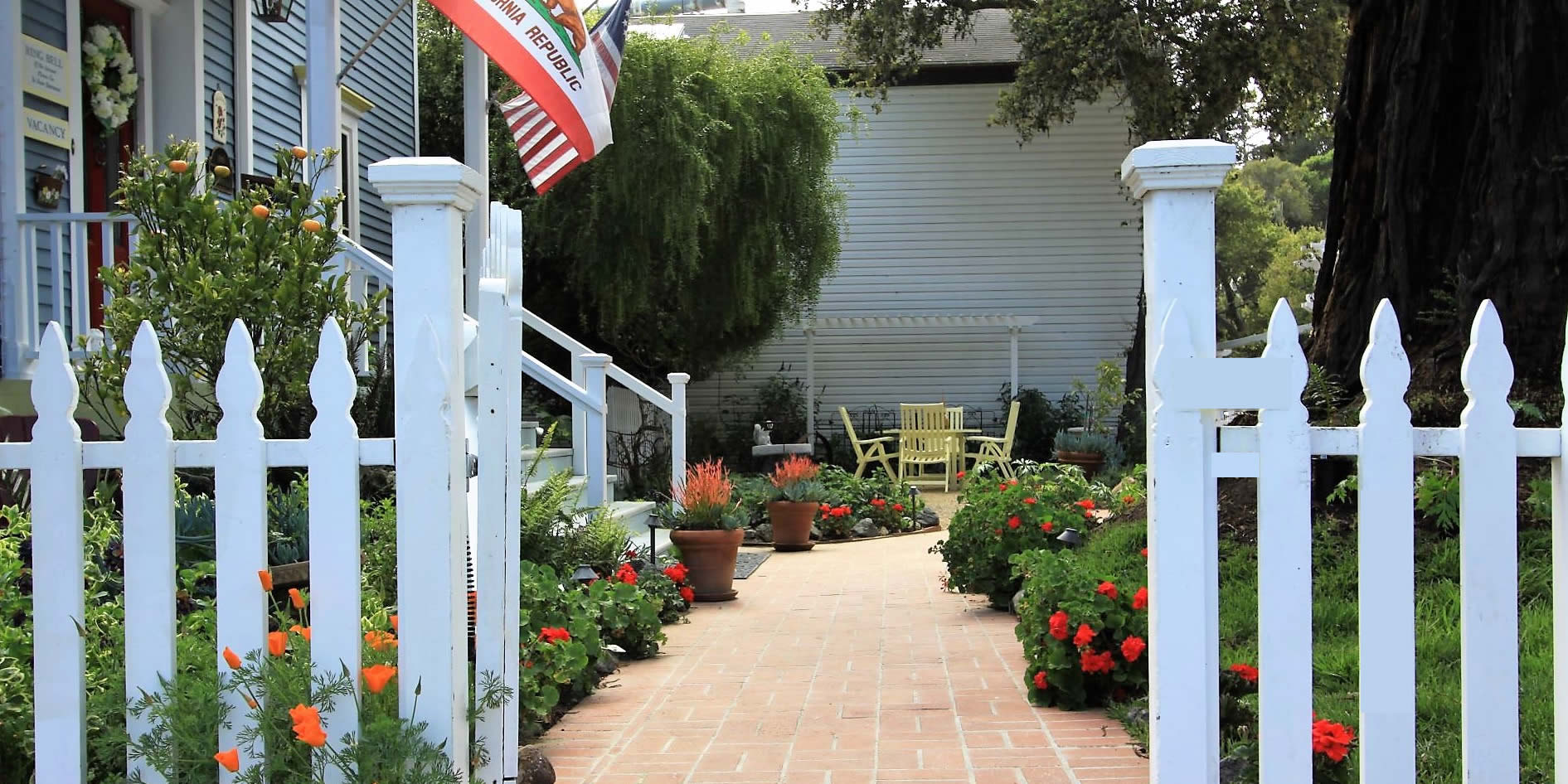 olallieberry inn gardens and gate into the bed and breakfast with flags flying