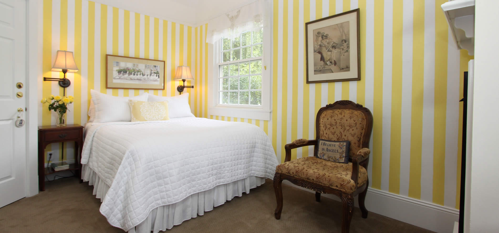 cambria bed and breakfast guestroom - bed with yellow striped wall paper and sitting chair